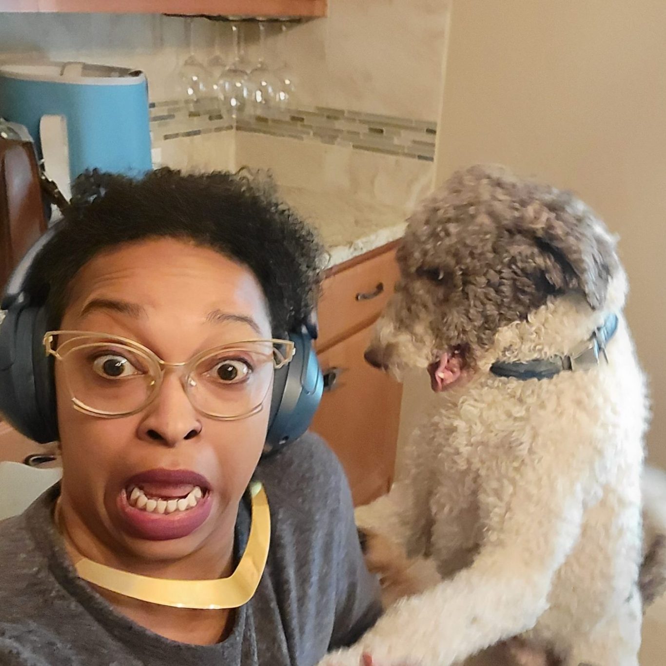 Smiling person with curly hair, colorful glasses, and vibrant lipstick.